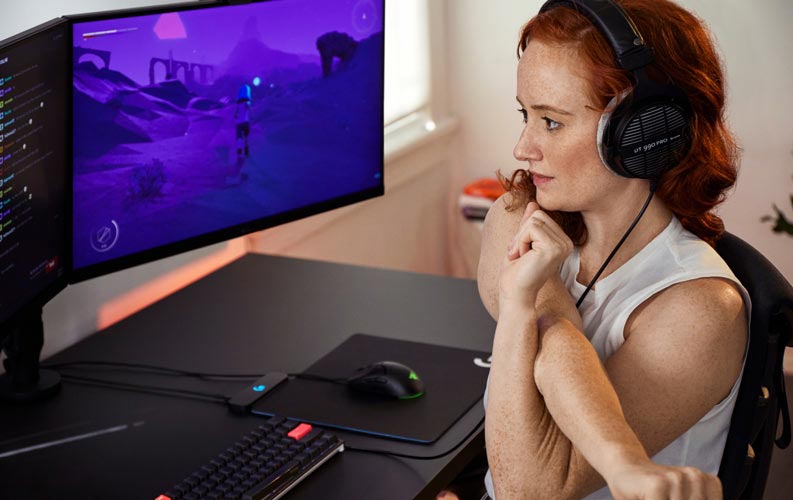 Esports doctor Lindsey Migliore in front of Gaming set up with dual monitors on Ollin monitor arms