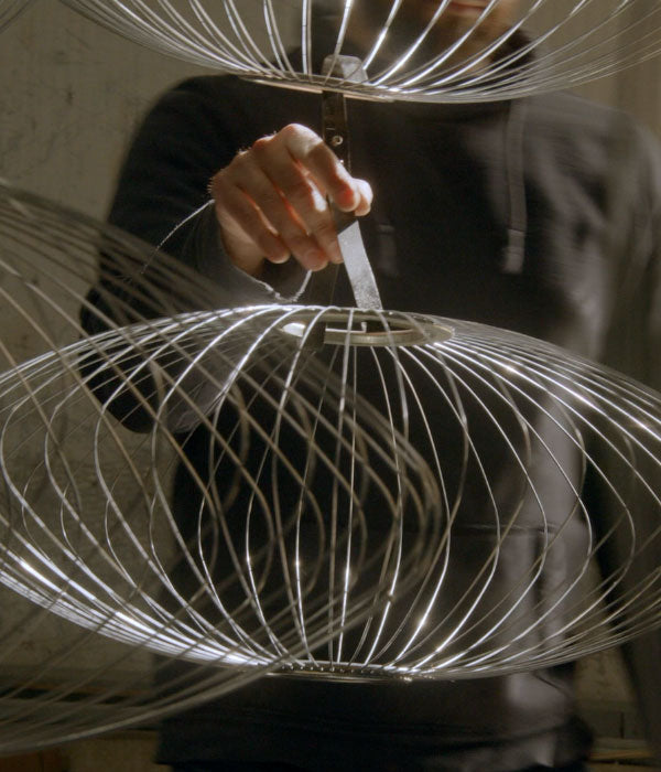 The stainless steel frame of a Nelson Bubble Pendant being handled during manufacture.