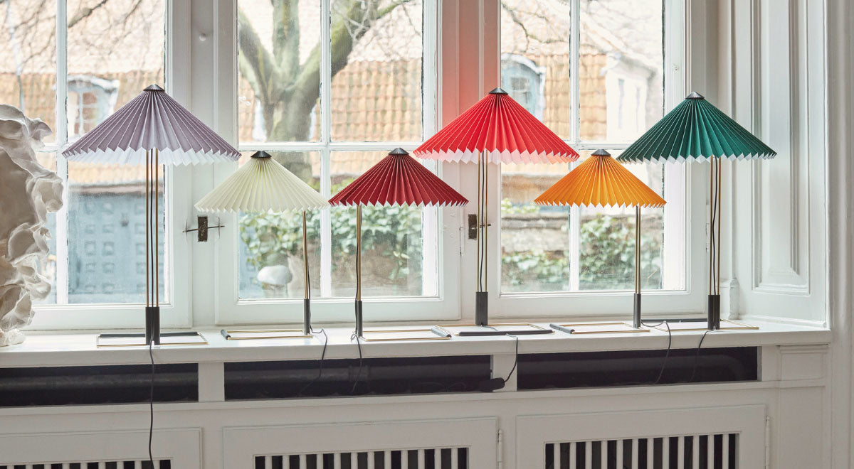 Six HAY Matin table lamps on a windowsill in a range of colours.
