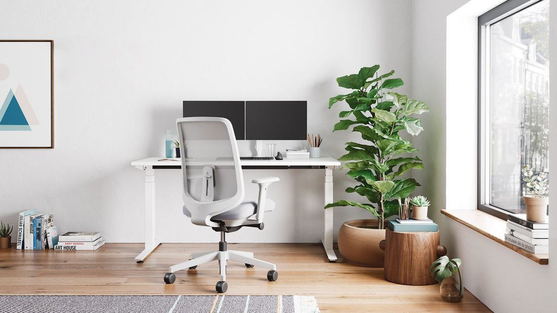 A white Nevi sit stand desk by Herman Miller as part of a light home office.