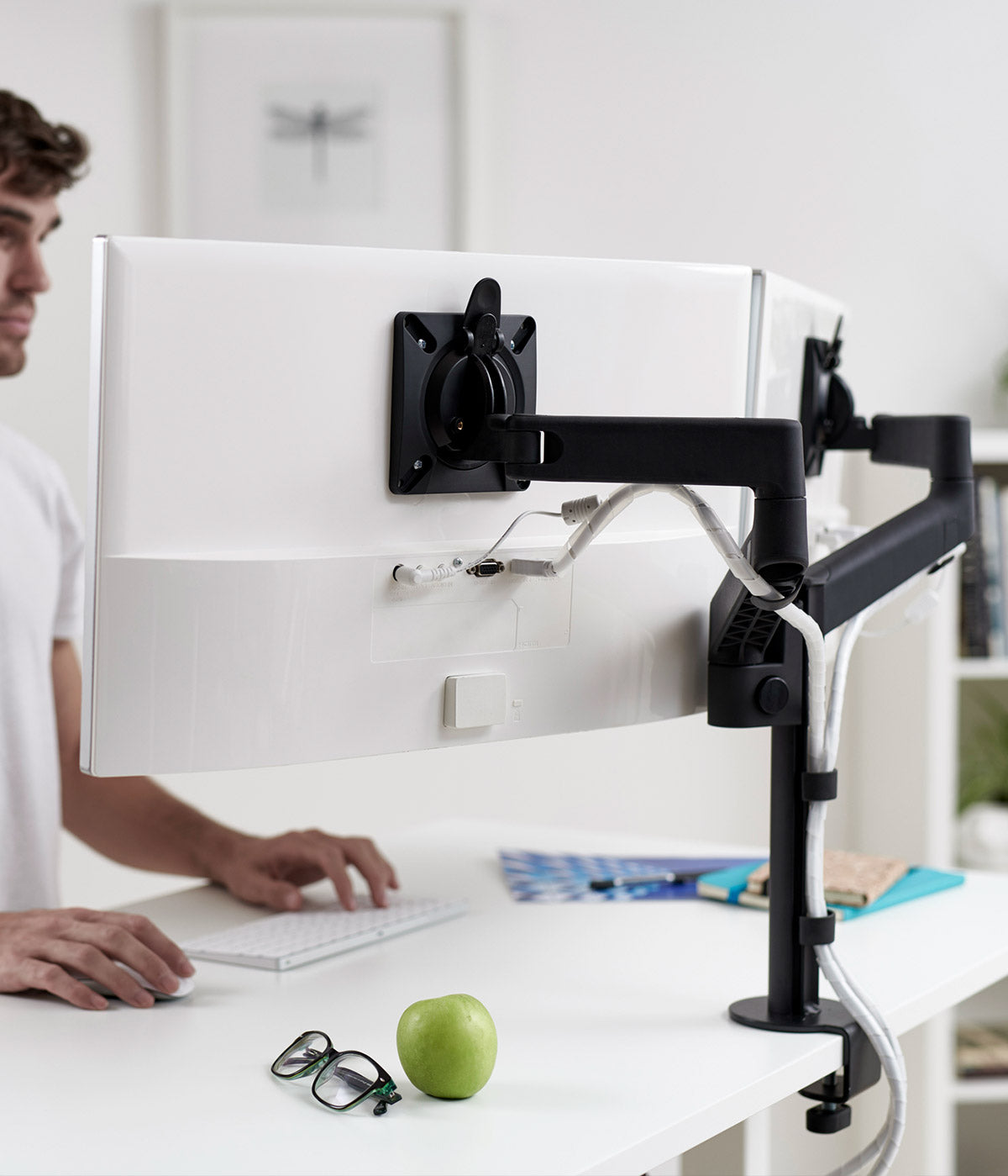 A black CBS Lima dual monitor arms supporting two screens on a sit-stand desk.