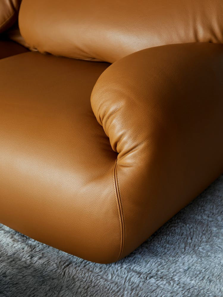 Close-up of a tan leather Luva sofa by Herman Miller, showing the curved sofa arm and the fabric texture.