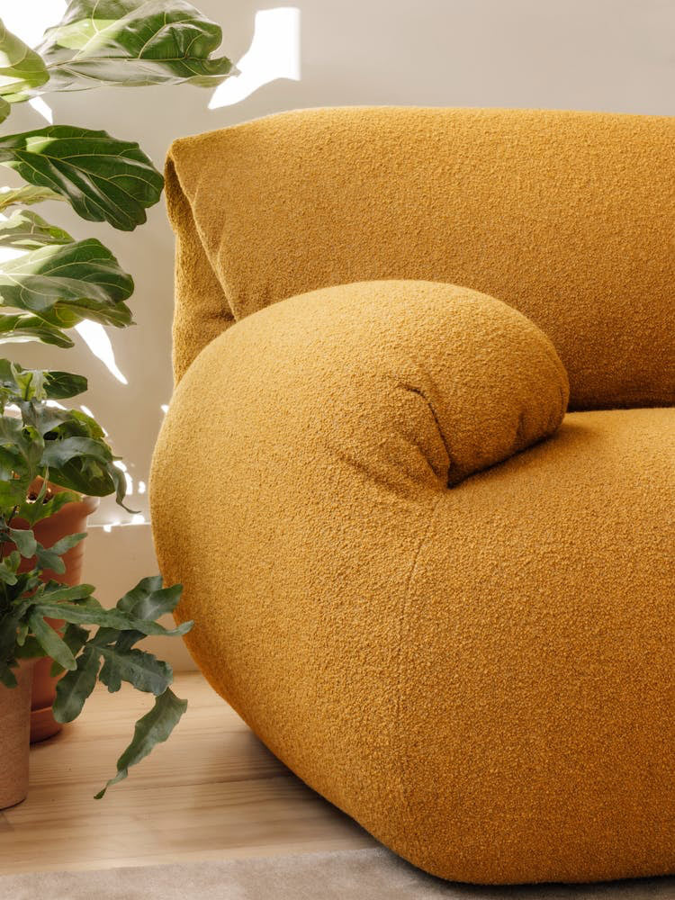 Close-up of a mustard yellow Luva sofa in Whim fabric, showing the curved sofa arm and the fabric texture.