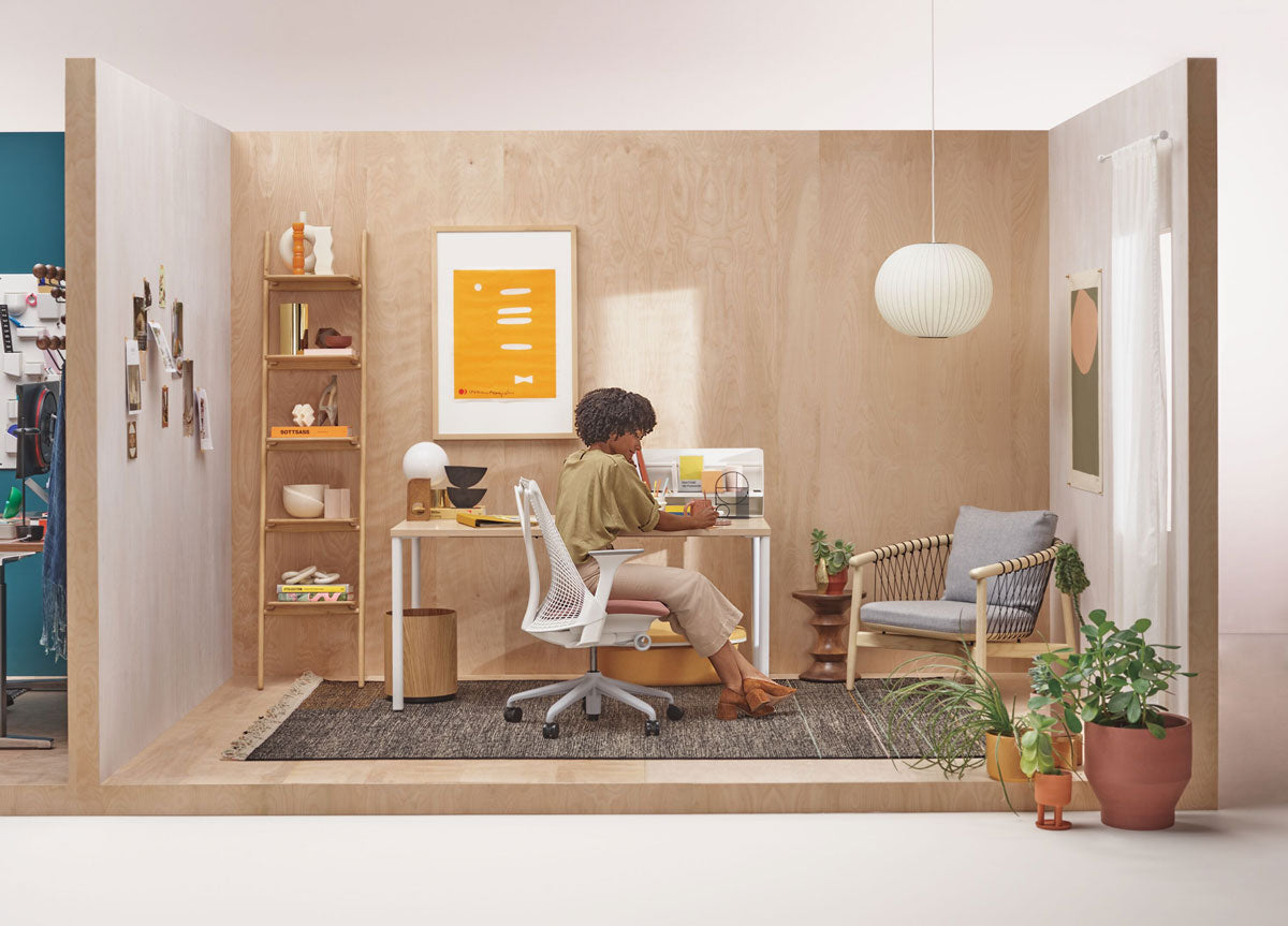 Lady sat at desk in a neutral home office setting in a Sayl office chair in white in front of OE1 desk with white legs and pale wood top