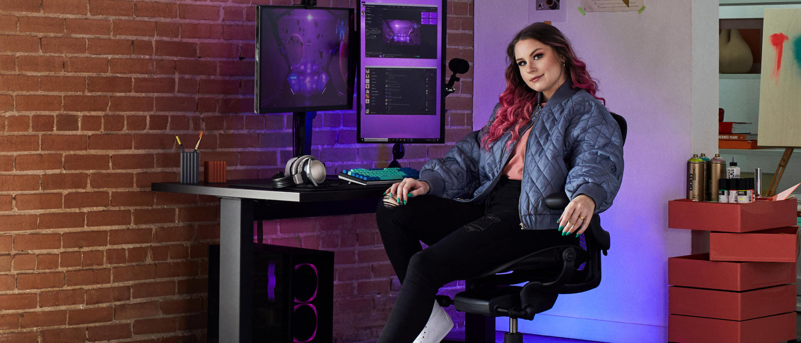 Photo of gamer Electra facing camera sat on Aeron gaming onyx black  in front of Nevi gaming desk in black with Ollin monitor