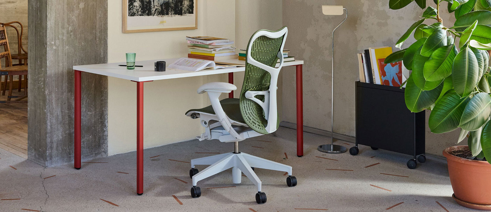 A warm home office featuring a green Mirra 2 office chair and white and red OE1 desk by Herman Miller.