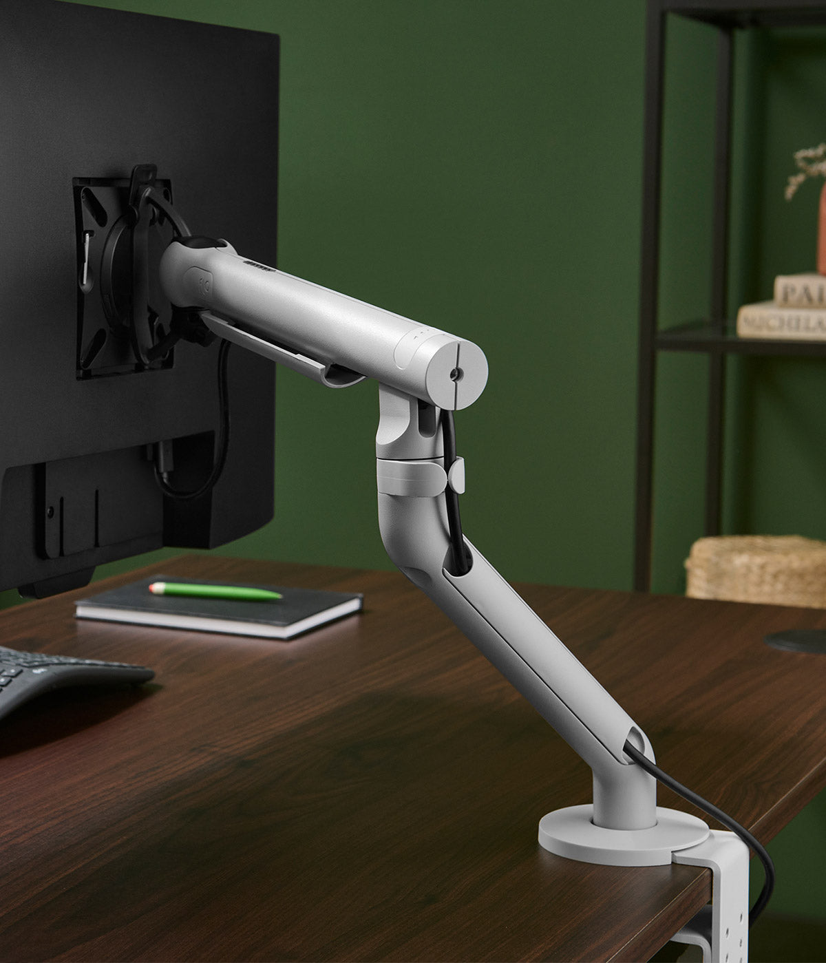 A white CBS Flo monitor arm attached to a walnut Jarvis desk.