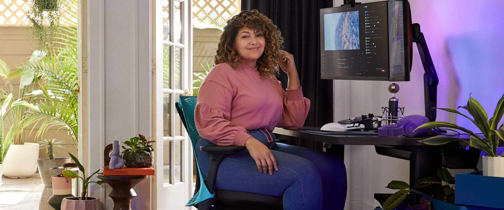 Photo of pro-gamer and voice actor Friskk sat at gaming set up in Sayl gaming chair in black and bright ocean deep blue with Nevi gaming desk in black