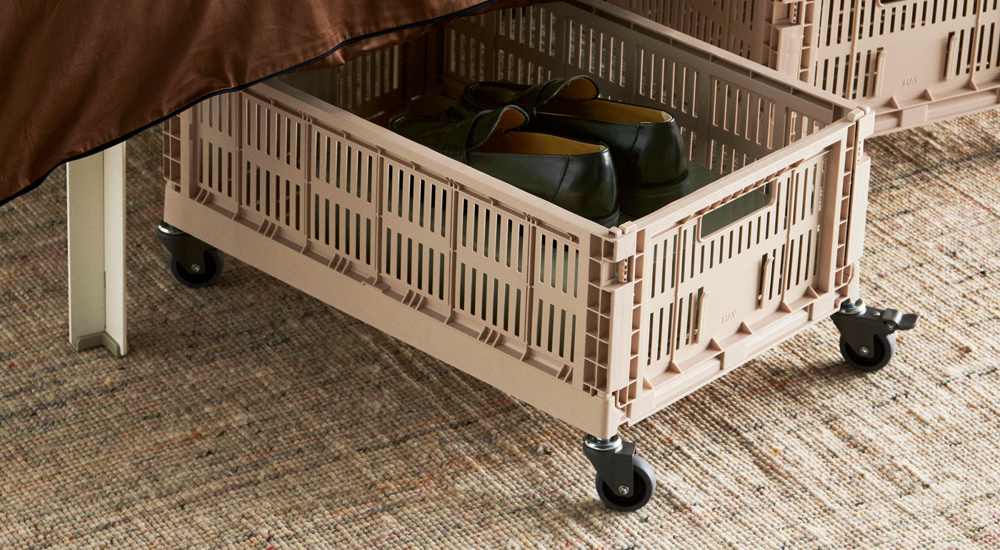 A beige HAY crate with lockable wheels.