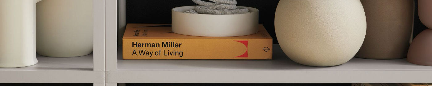 A copy of "Herman Miller - A Way of Living"  on a shelf amongst vases.