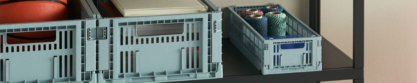 Pale blue collapsible crates in two sizes sat on ablack metal shelf.