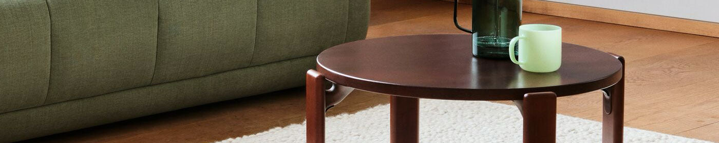 A HAY Rey coffee table in umber brownin the centre of a living room with natural tones.