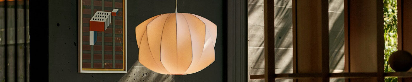 An illuminated George Nelson Propellor Bubble lamp ceiling pendant hanging in a wood and concrete living room.