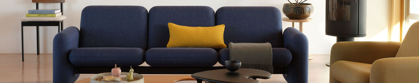 A wood-floored living room featuring a blue Herman Miller Wilkes sofa and yellow armchair.