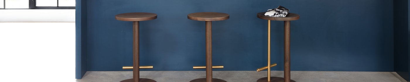 A lineup of three Herman Miller Spot stools in front of a deep blue kitchen counter.