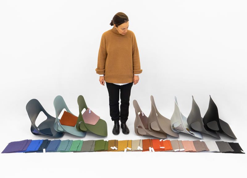Designer from Studio 7.5 looking down to floor at materials swatches and Zeph seats in a variety of colours