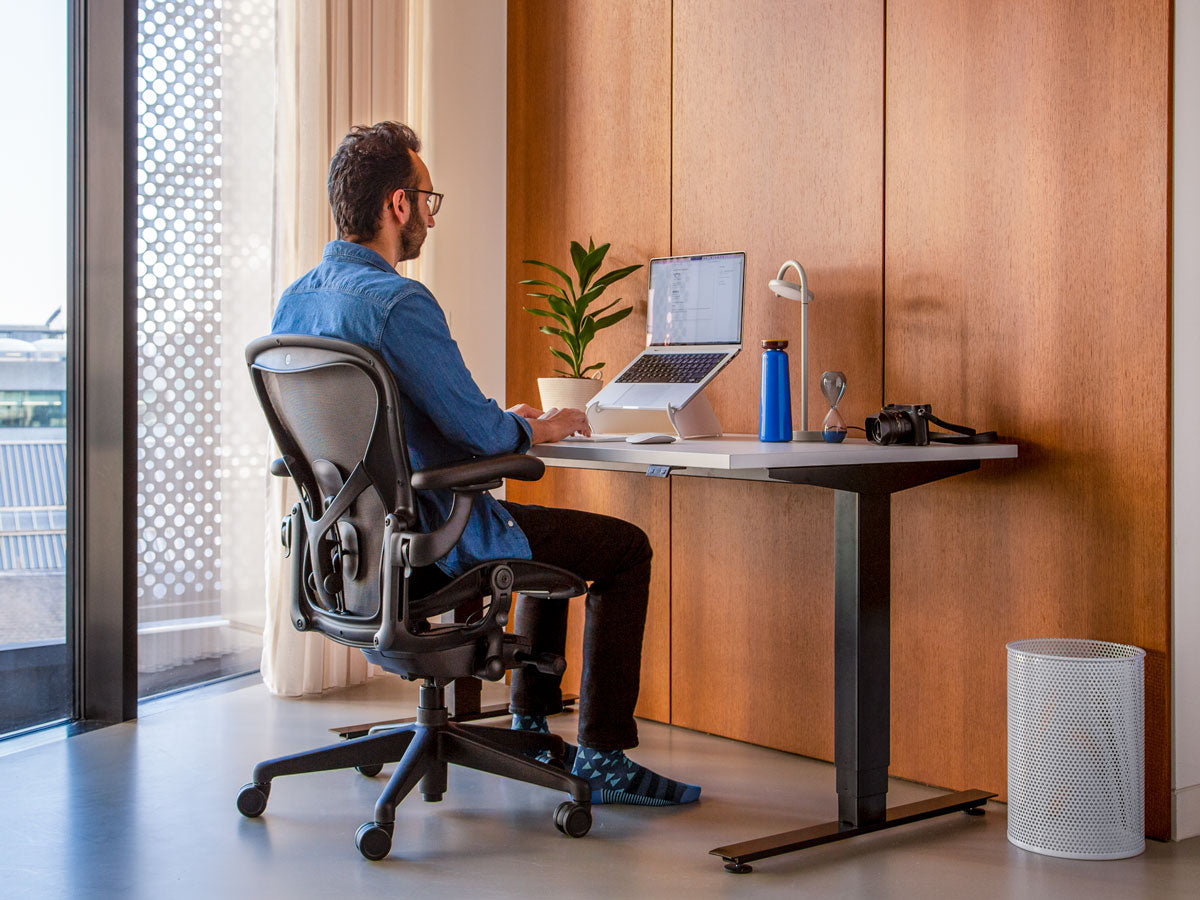 Photo of man sat in Aeron office chair in graphite correctly showing that feet should be on floor if sitting properly