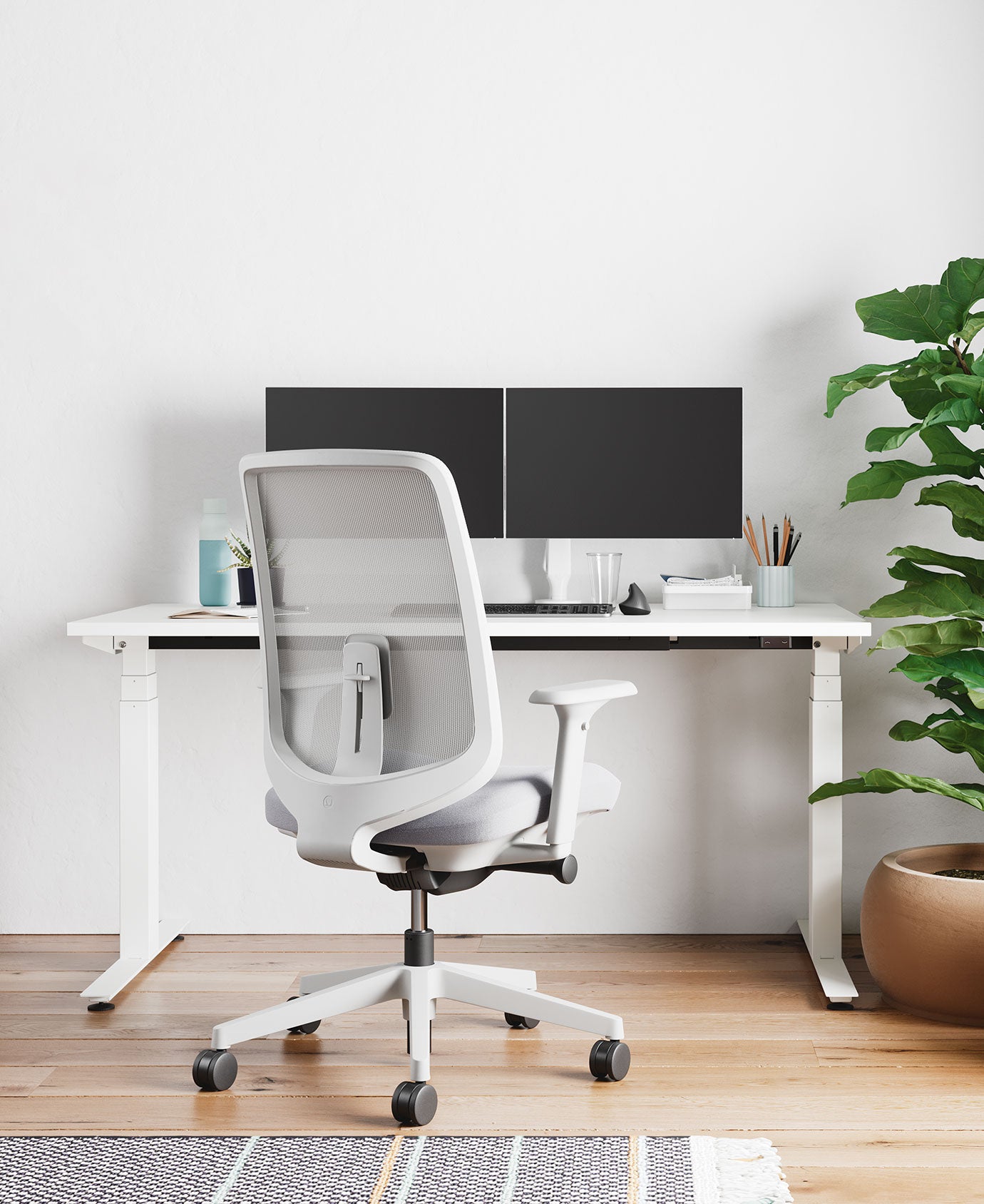Home office with Verus office chair in mineral white with pale grey seat pad, infront of Nevi sit-stand desk in white with dual screens on monitor arms