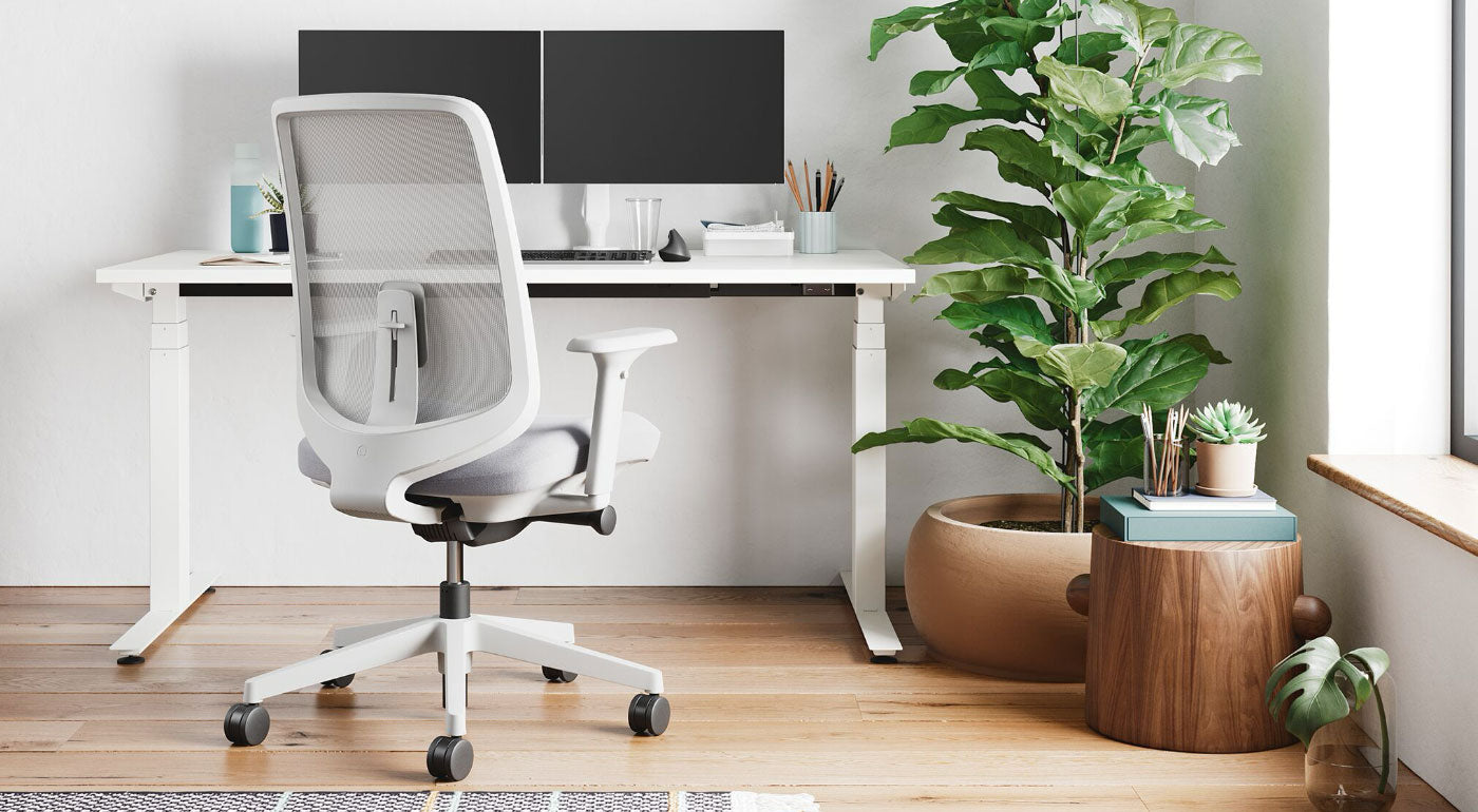 A white and blue Verus office chair by Herman Miller, positioned in front of a white Nevi standing desk with a white 'The Telegraph Best Buy 2024' sticker.