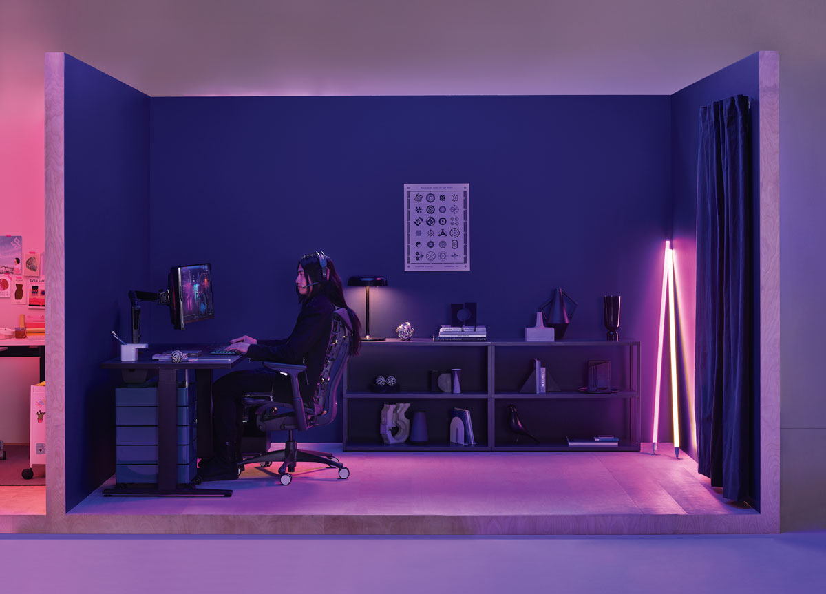 Gaming set up office with lady playing sat in Logitech Embody gaming chair in black with Nevi gaming desk in black with Hay neon tube lighting in the corner