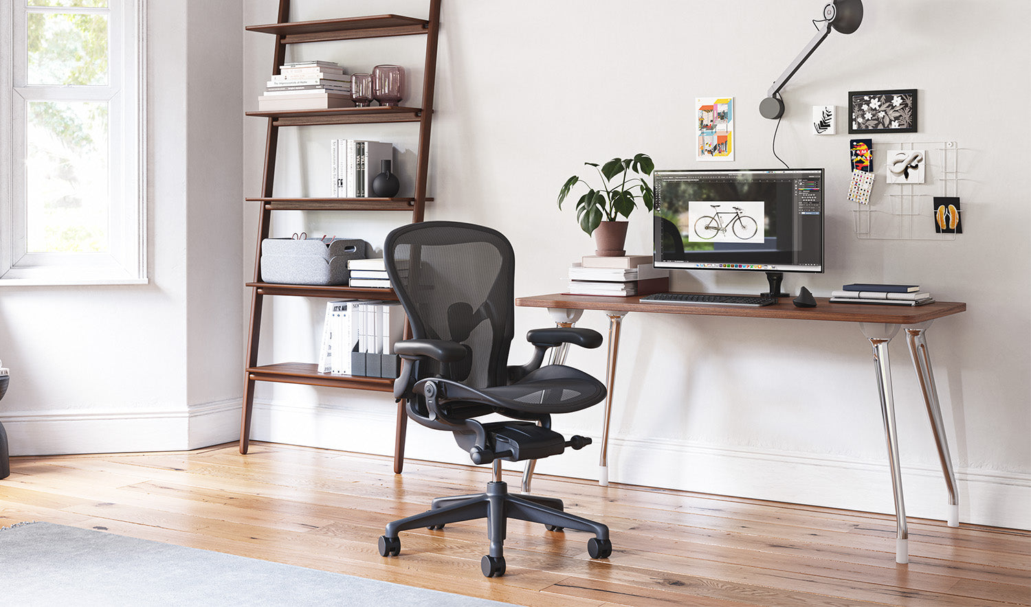 A graphite Aeron chair in front of an AbakEnvironments desk. A Hew side table and Folk shelving unit are against the walls in a home office.